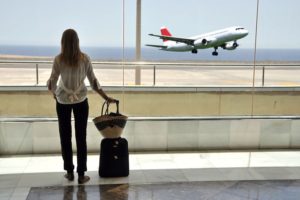 Girl at the airport window looking to the ocean